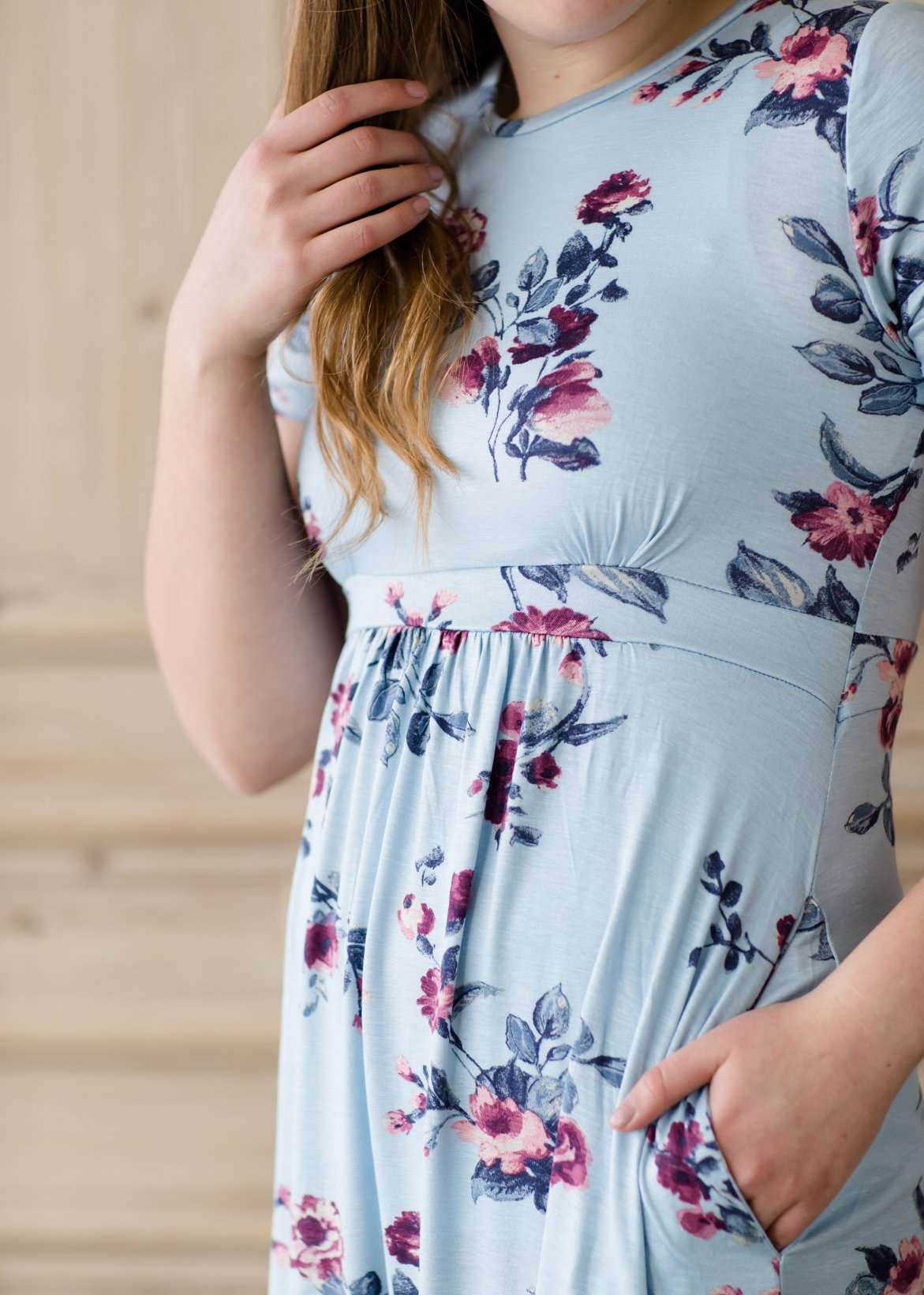 Woman wearing a light blue modest empire waist midi dress with flowers on it