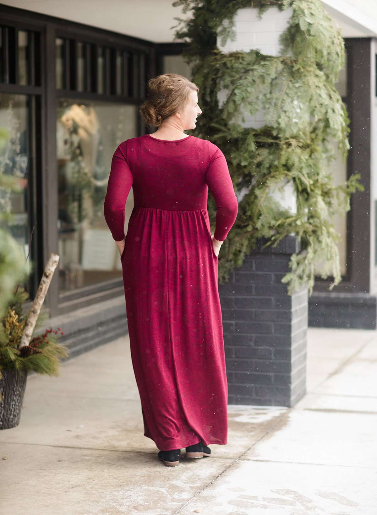 Woman wearing a wine colored maxi dress made of a hacci material standing outside of Inherit Clothing Company