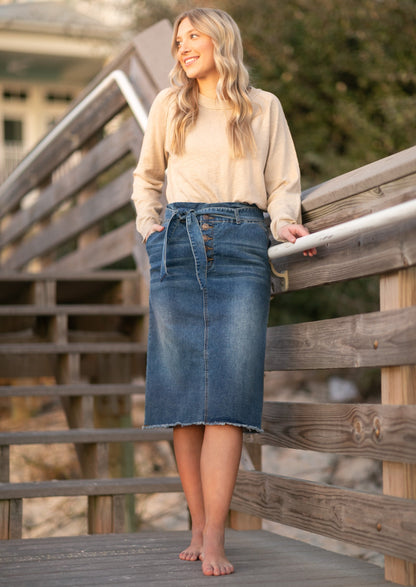 This midi length skirt is made out of stretch denim, with a paperbag stretch waist, with a matching belt, and a raw hem.